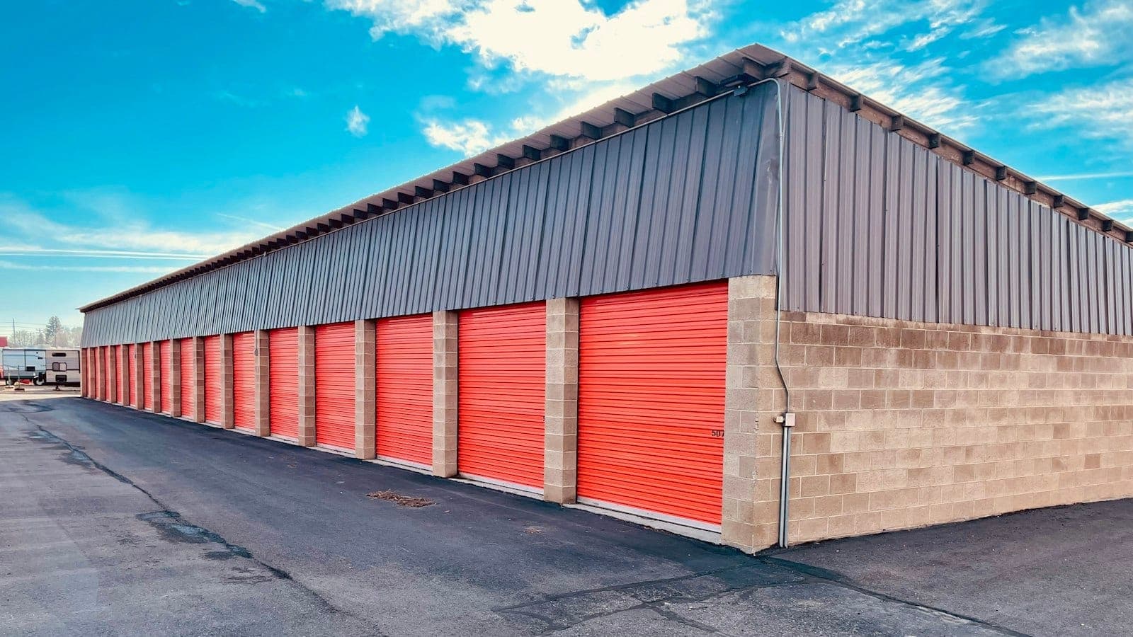 Stacked moving boxes and blanket-wrapped furniture inside a clean Denver storage warehouse with a moving truck in the background