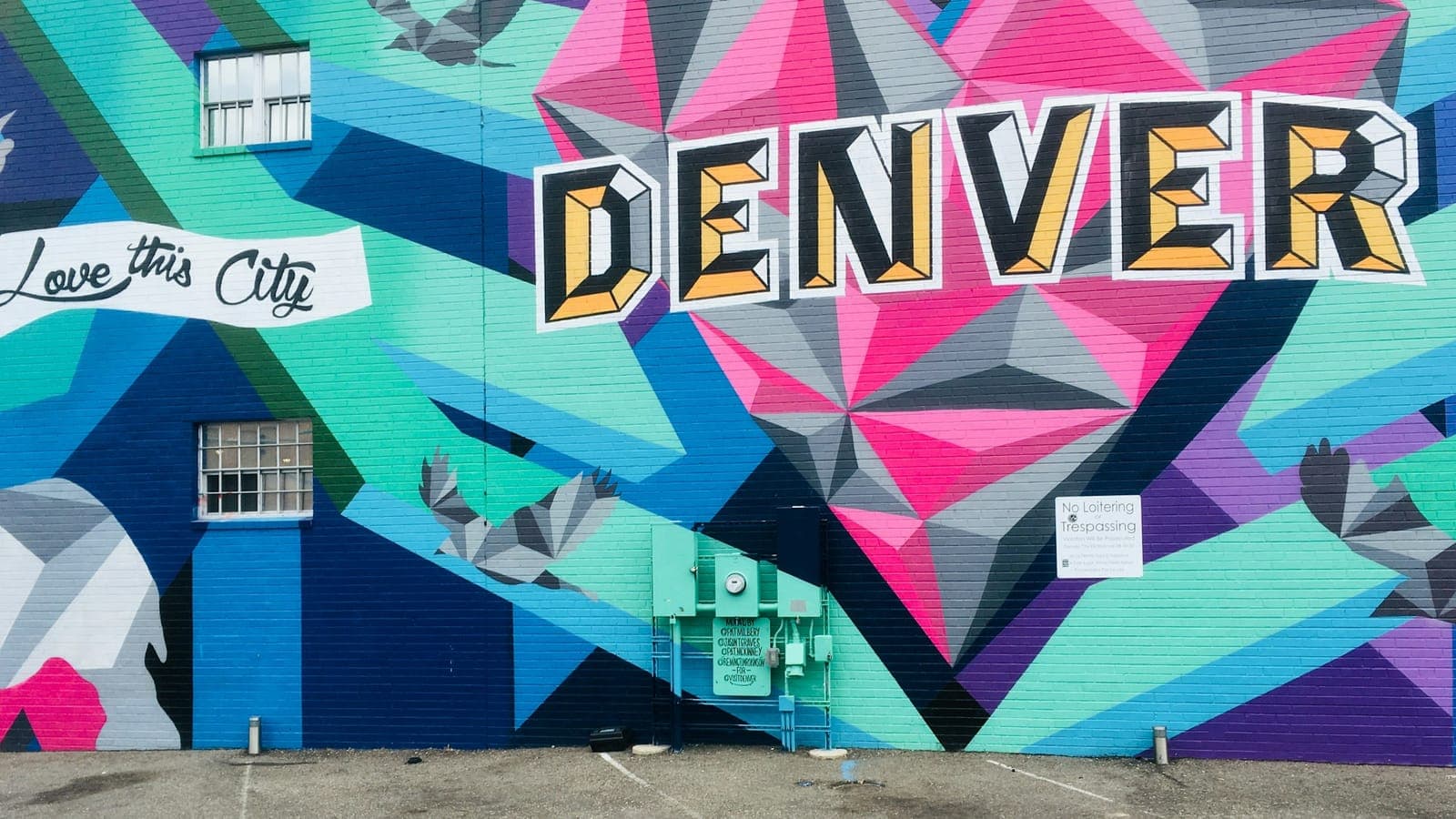 Young renter carrying moving boxes into a Denver apartment building with the Front Range in the background